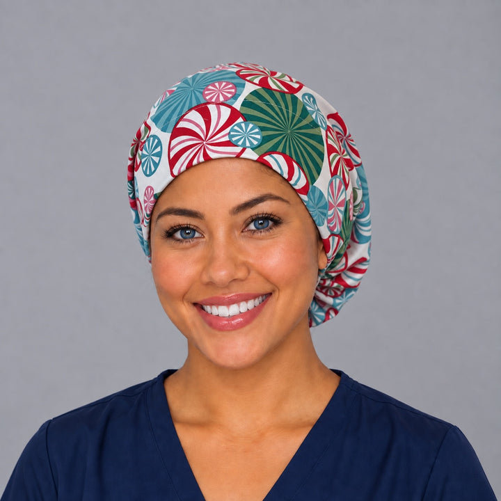 Woman wearing a peppermint swirl Euro scrub cap, front view — red, teal and pink peppermint candies on cream, adjustable holiday surgical hat