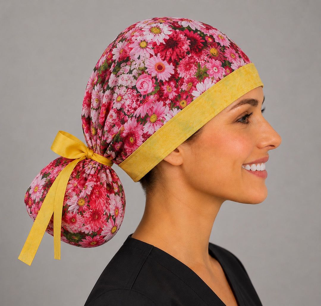 Pink daisy floral ponytail scrub cap left front angle showing full ponytail pouch of pink and white daisies and yellow ribbon bow