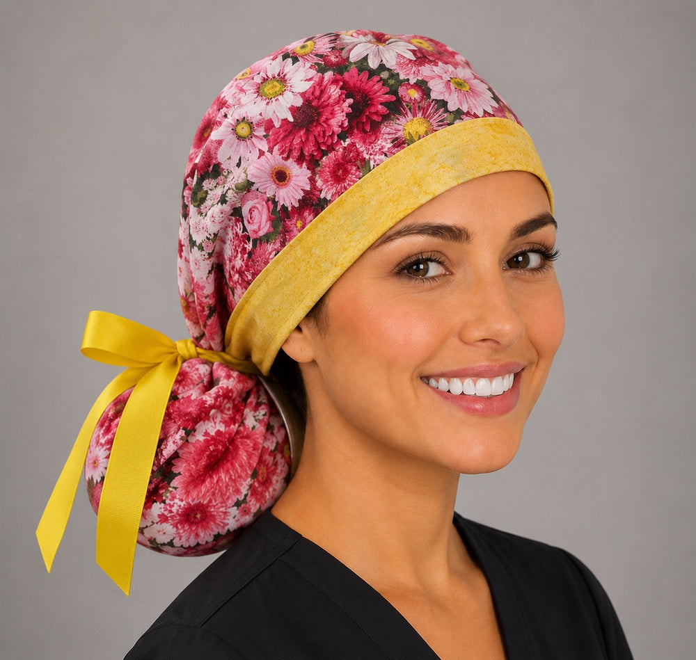 Pink daisy floral ponytail surgical cap left side profile showing gathered ponytail pouch of pink daisies and yellow grosgrain ribbon bow