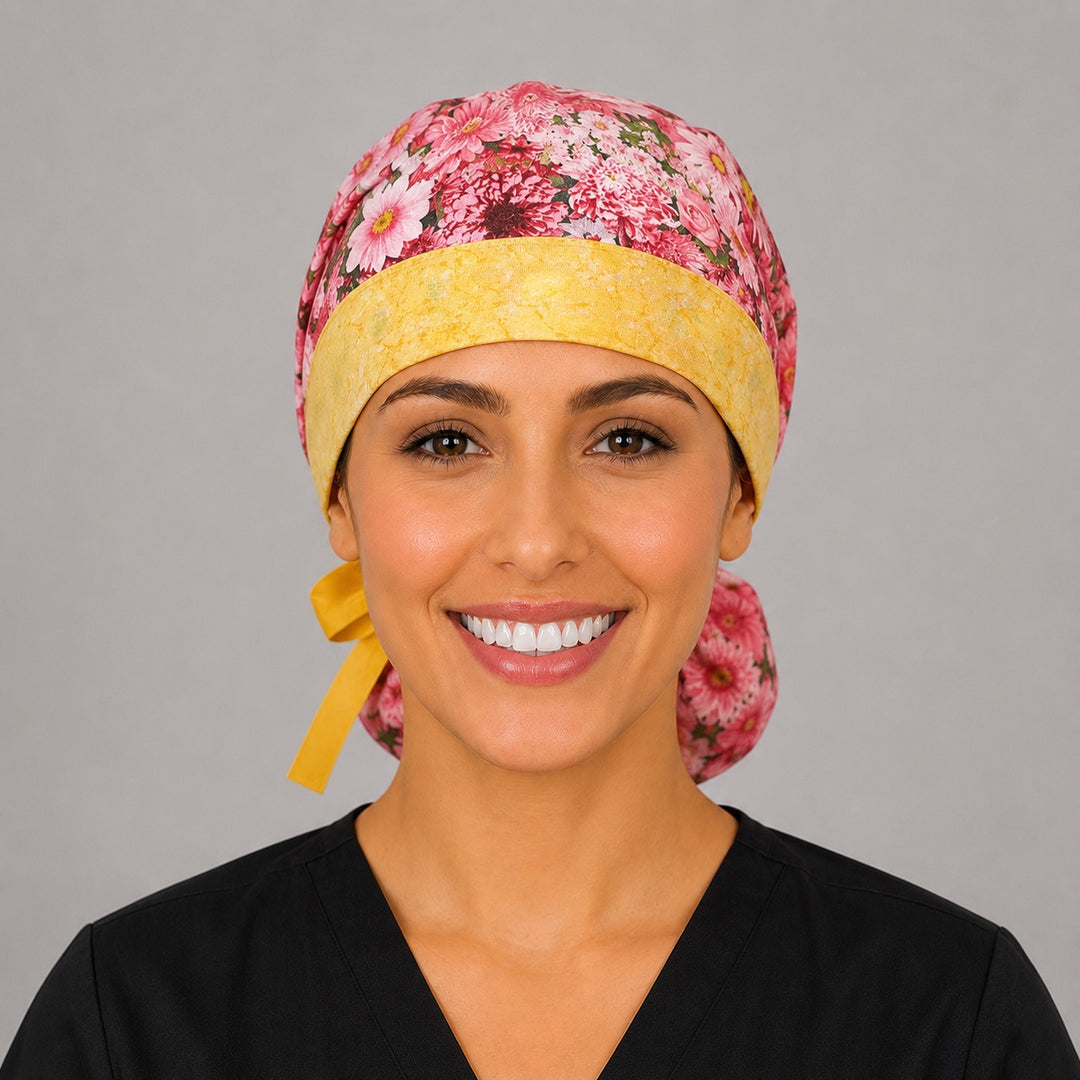 Pink daisy floral ponytail nurse cap right three-quarter angle on smiling model showing pink daisies, red flowers and yellow band