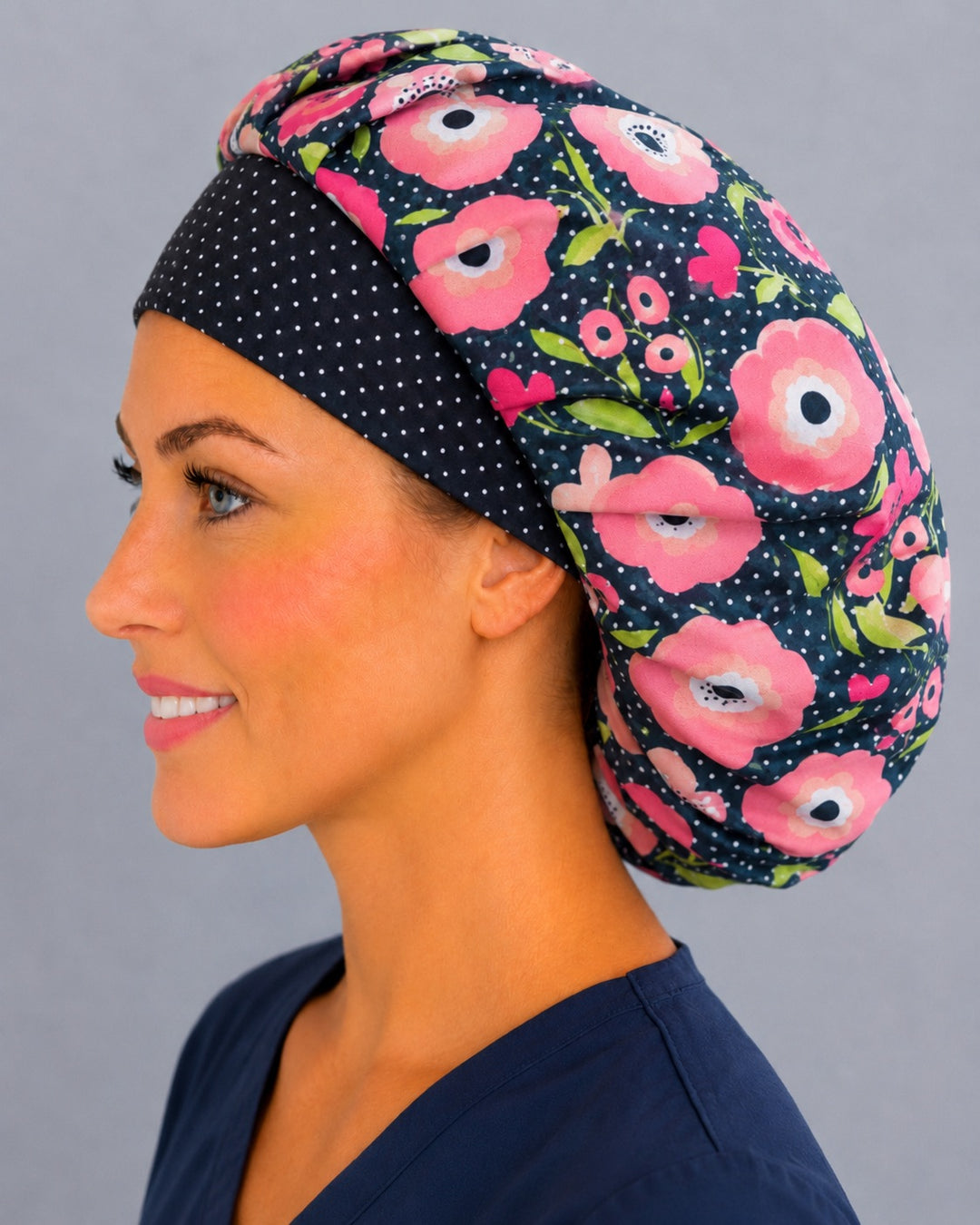 Pink floral bouffant scrub cap angled smiling view — roomy elastic-back cap for L&amp;D nurses with long thick hair