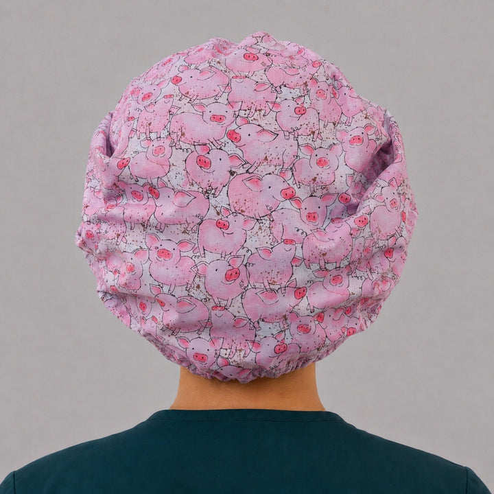 Back view of the pink pig bouffant scrub cap — full gathered fit showing piglets and mud speckles across the crown