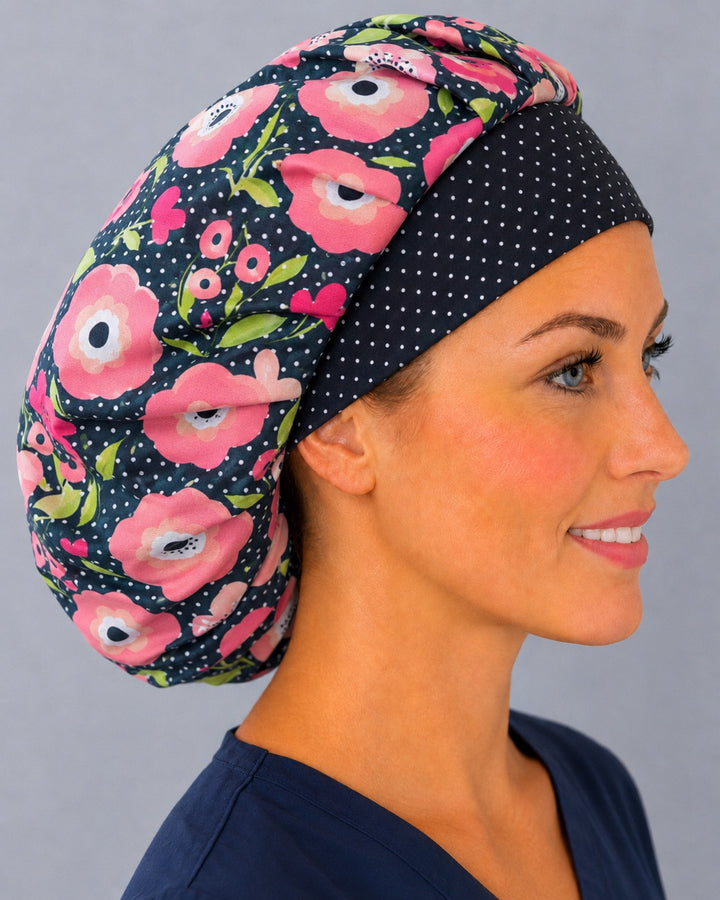 Woman wearing a pink poppy polka dot bouffant scrub cap, front view — pink florals on black with white dots, adjustable women&