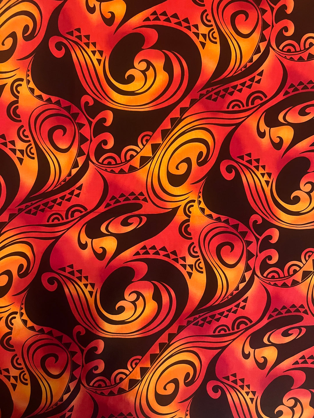 Close-up of the 100% premium cotton fabric swatch used for the Polynesian tribal scrub cap for men, red and orange tribal tattoo print detail