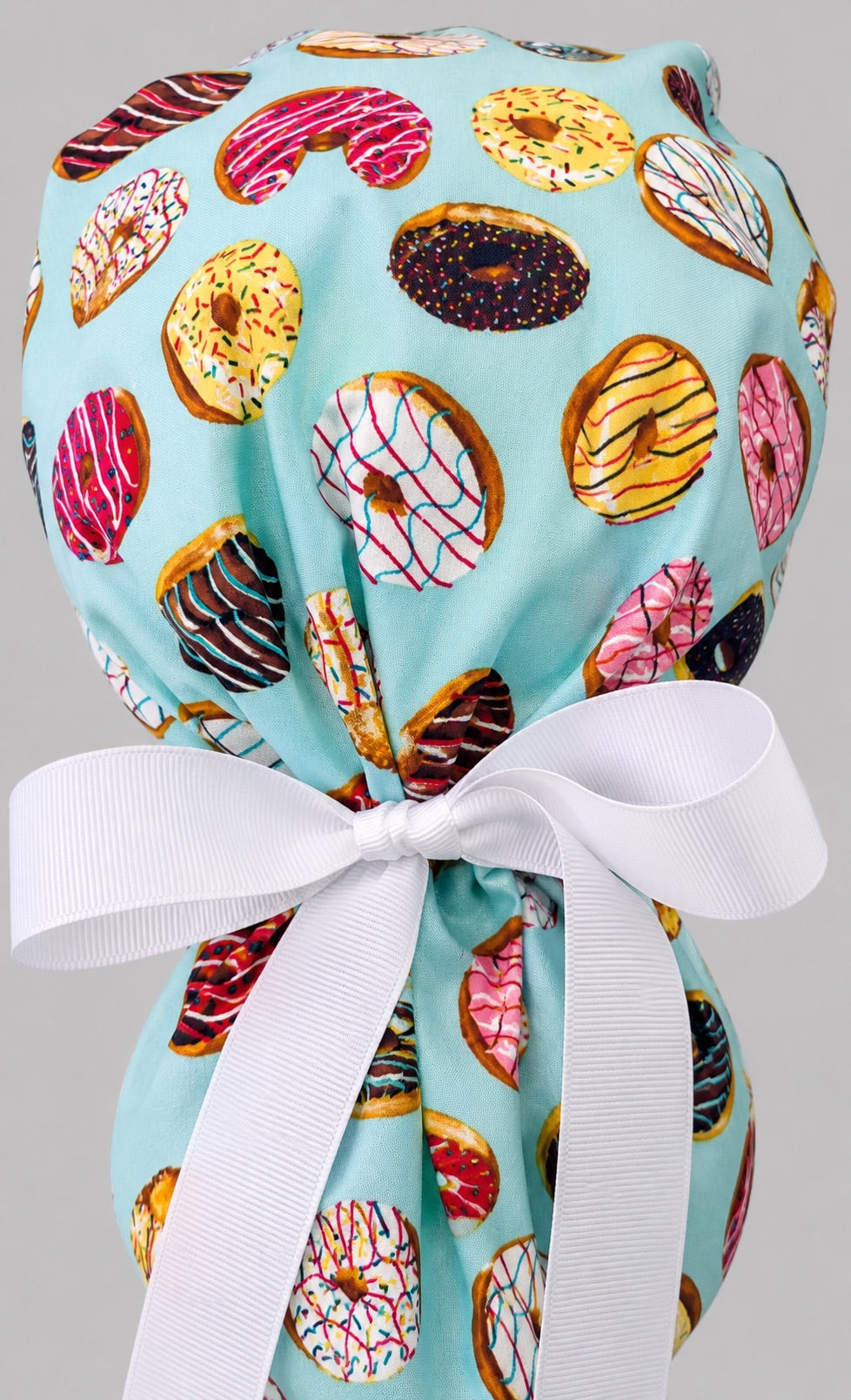 Back view close-up of donut print ponytail scrub cap ponytail pouch with white grosgrain bow tie