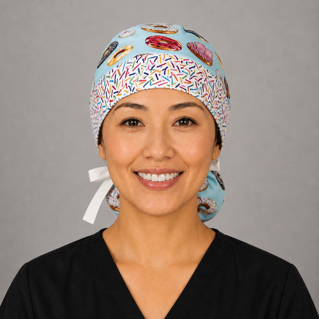 Front view of donut print ponytail scrub cap for women with colorful frosted donuts and rainbow sprinkle headband