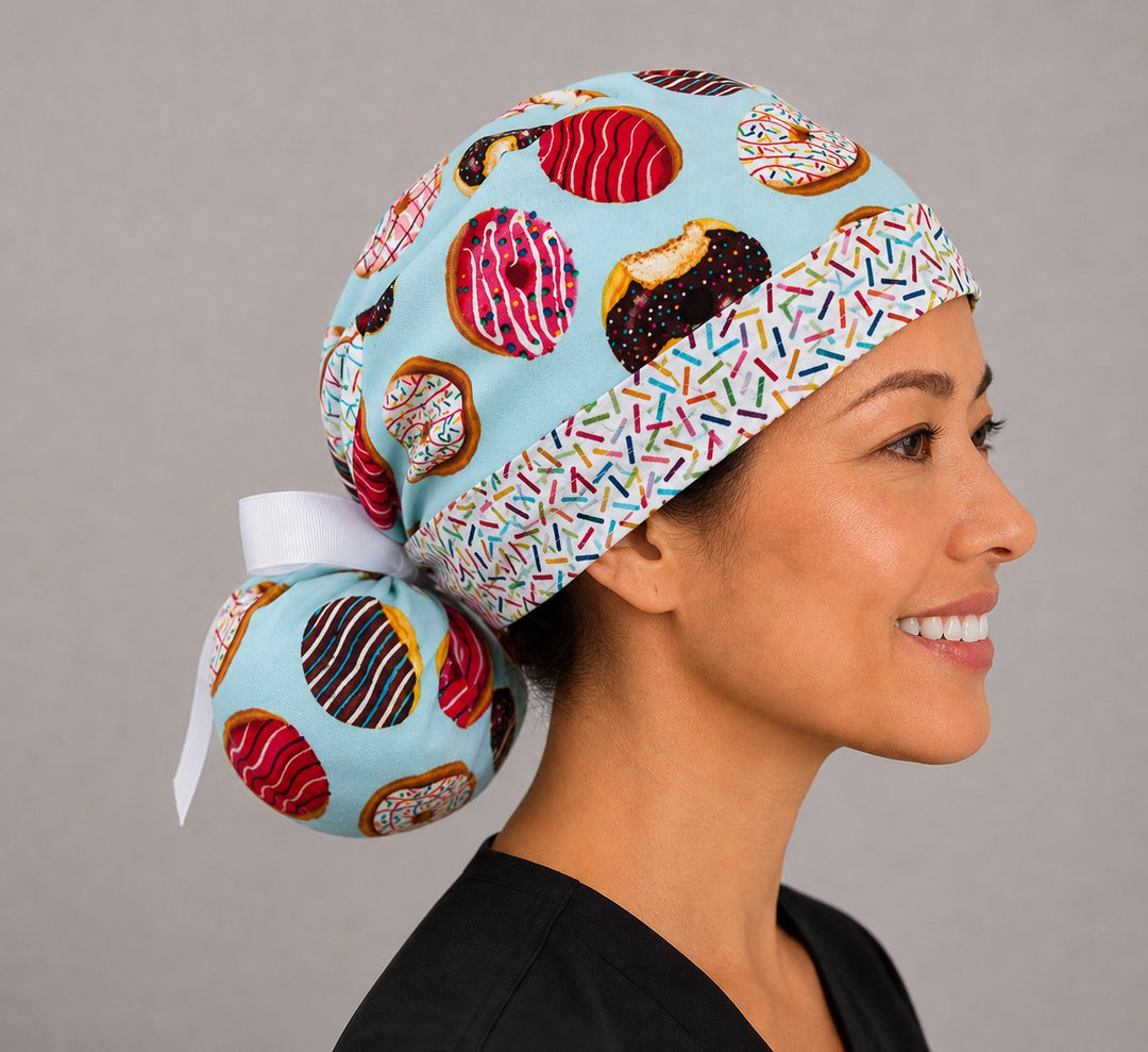 Side view of donut print ponytail scrub cap showing roomy pouch holding long hair with white ribbon tie