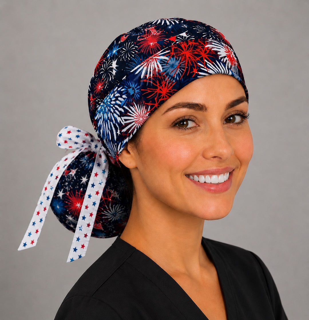 Three-quarter view of patriotic fireworks ponytail surgical cap for women in red white and blue with ponytail pouch