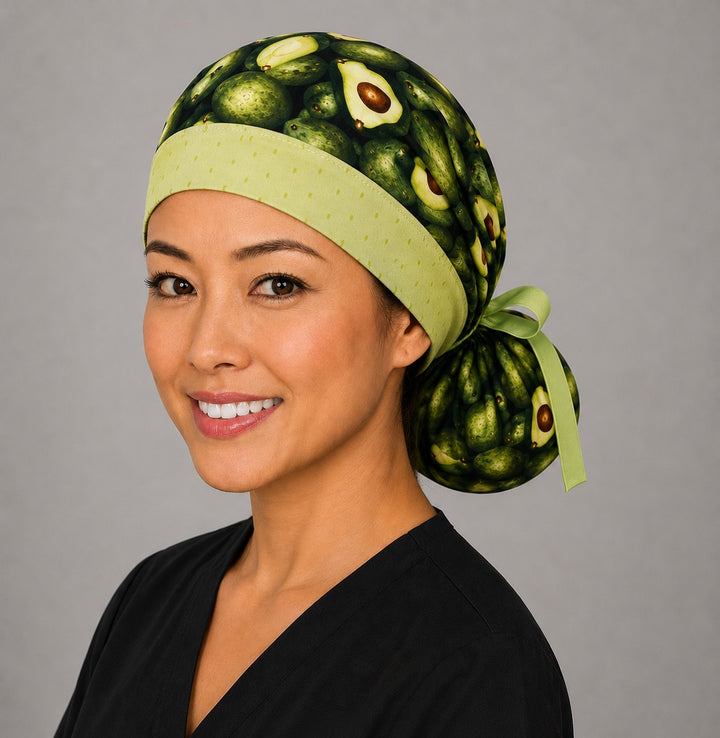 Avocado print ponytail scrub cap right three-quarter angle on smiling model showing avocado halves and light green trim