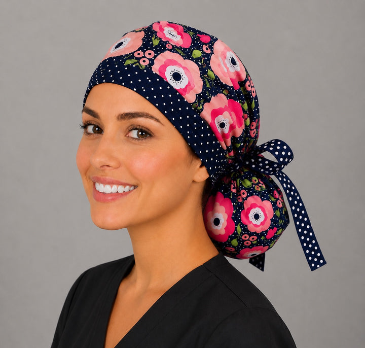 Black floral polka dot ponytail scrub cap right angle on model showing pink and coral poppies with polka dot band and ribbon