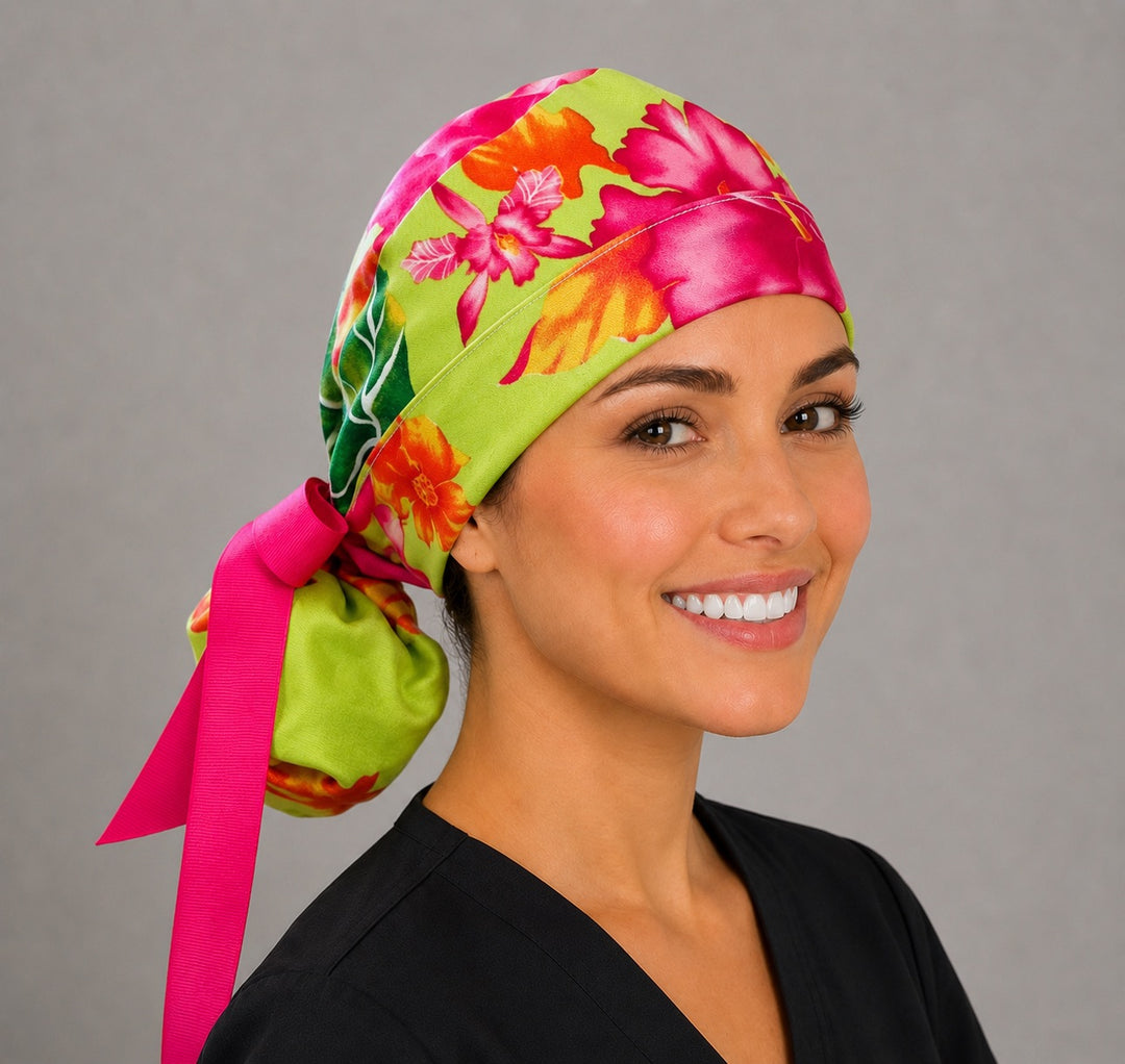 Hawaiian hibiscus tropical ponytail nurse cap left three-quarter angle showing gathered ponytail pouch of pink hibiscus flowers and hot pink ribbon bow