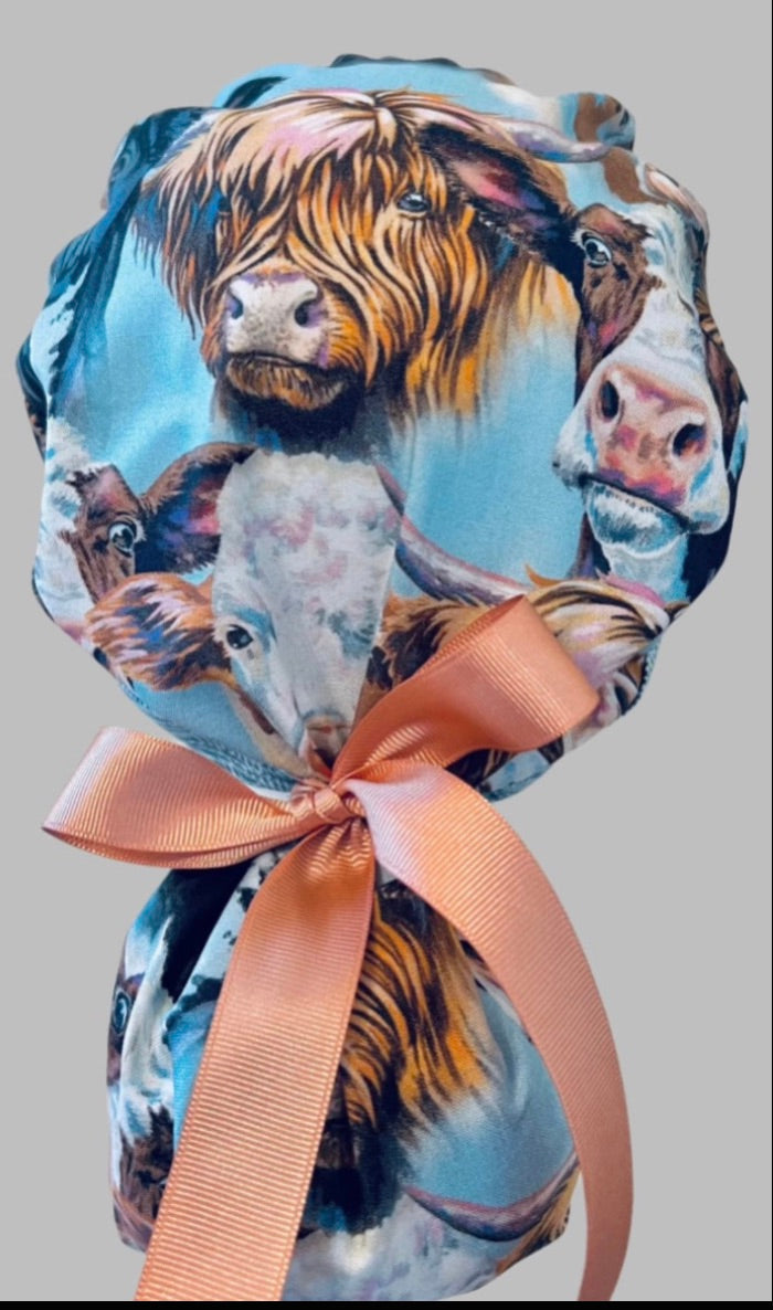 Highland cow ponytail scrub cap back view close-up showing cow print detail and tied peach ribbon bow