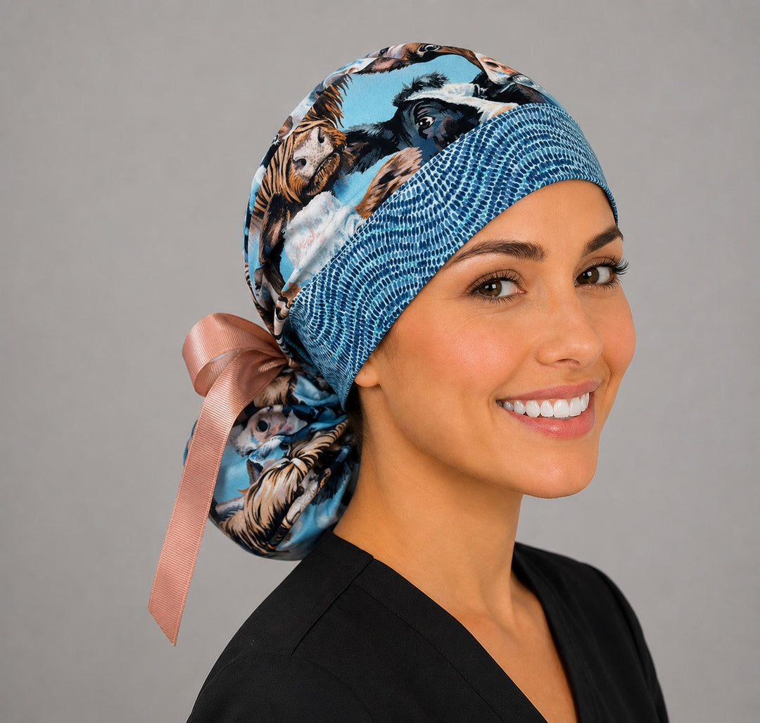 Highland cow ponytail nurse cap three-quarter angle showing cow faces print and adjustable ribbon tie-back