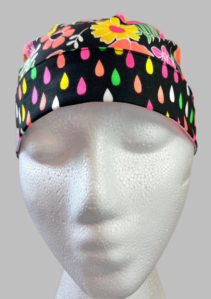 Neon floral ponytail scrub cap front band detail on mannequin showing pink green yellow flowers and teardrop trim