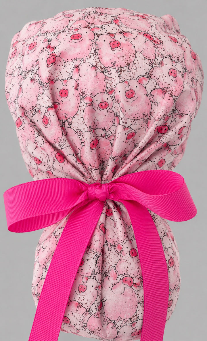 Pink pig ponytail scrub cap right side profile showing gathered pouch of cartoon pigs and long hot pink ribbon ties