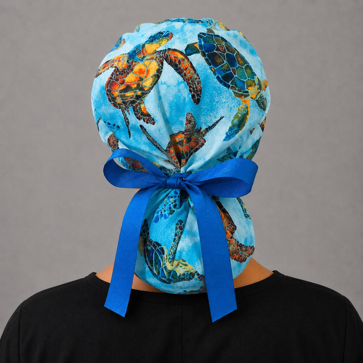 Sea turtle tropical ocean ponytail scrub cap back view on mannequin showing gathered pouch of colorful ocean turtles and royal blue ribbon bow