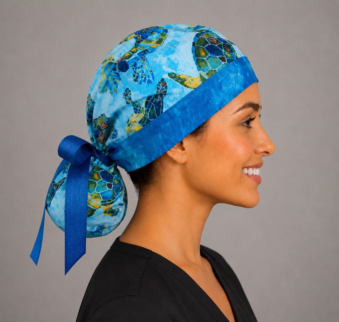 Sea turtle tropical ocean ponytail scrub cap left profile view showing full ponytail pouch of ocean turtles and long royal blue ribbon ties