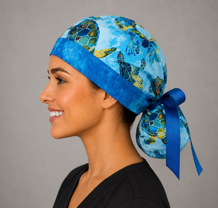 Sea turtle tropical ocean ponytail surgical cap left side profile with royal blue band and gathered pouch of blue and green turtles