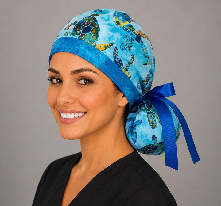 Sea turtle tropical ocean ponytail nurse cap right three-quarter angle showing gathered ponytail pouch of colorful turtles and royal blue ribbon bow