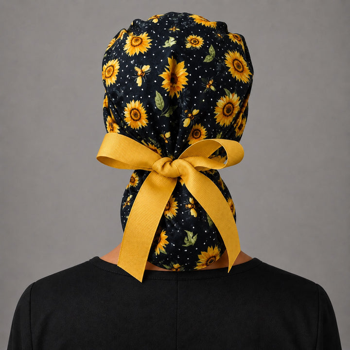 Sunflower and bee ponytail surgical cap left side profile showing gathered ponytail pouch of sunflowers and honey bees with gold ribbon tie