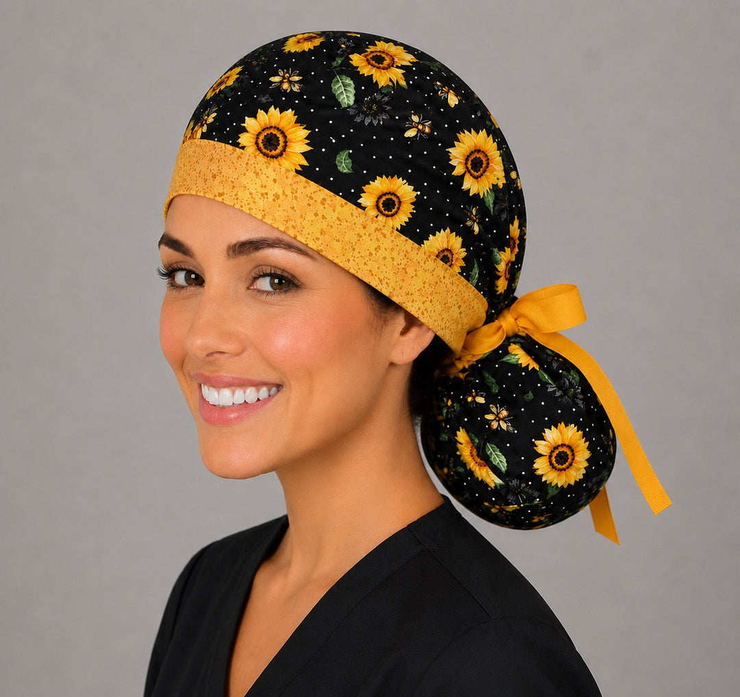 Sunflower and bee ponytail scrub cap right angle on smiling model showing sunflowers, honey bees on black polka dots and gold band