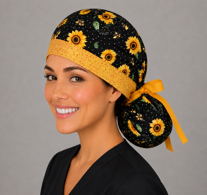 Sunflower and bee ponytail scrub cap right angle on smiling model showing sunflowers, honey bees on black polka dots and gold band