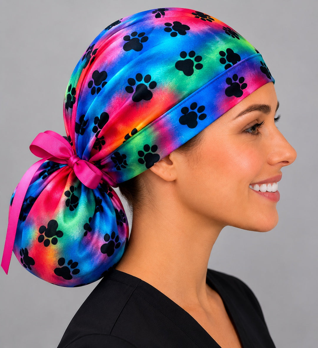 Tie dye puppy paw rainbow ponytail surgical cap left side profile showing full gathered ponytail pouch and hot pink grosgrain bow