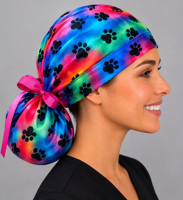Tie dye puppy paw rainbow ponytail surgical cap left side profile showing full gathered ponytail pouch and hot pink grosgrain bow
