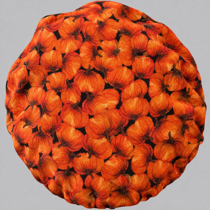 Back view of the pumpkin bouffant scrub cap — full gathered fit showing ripe orange pumpkins across the whole black crown