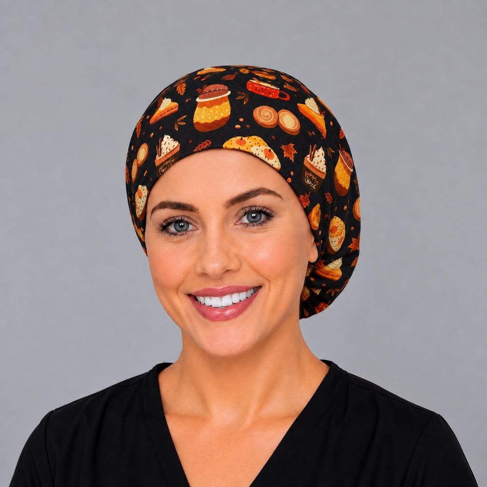 Woman wearing a fall pumpkin spice Euro scrub cap, front view — lattes, pumpkin pie and cupcakes on black, adjustable surgical hat