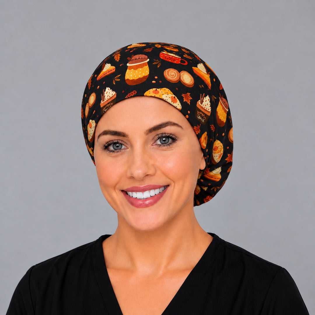 Woman wearing a fall pumpkin spice Euro scrub cap, front view — lattes, pumpkin pie and cupcakes on black, adjustable surgical hat