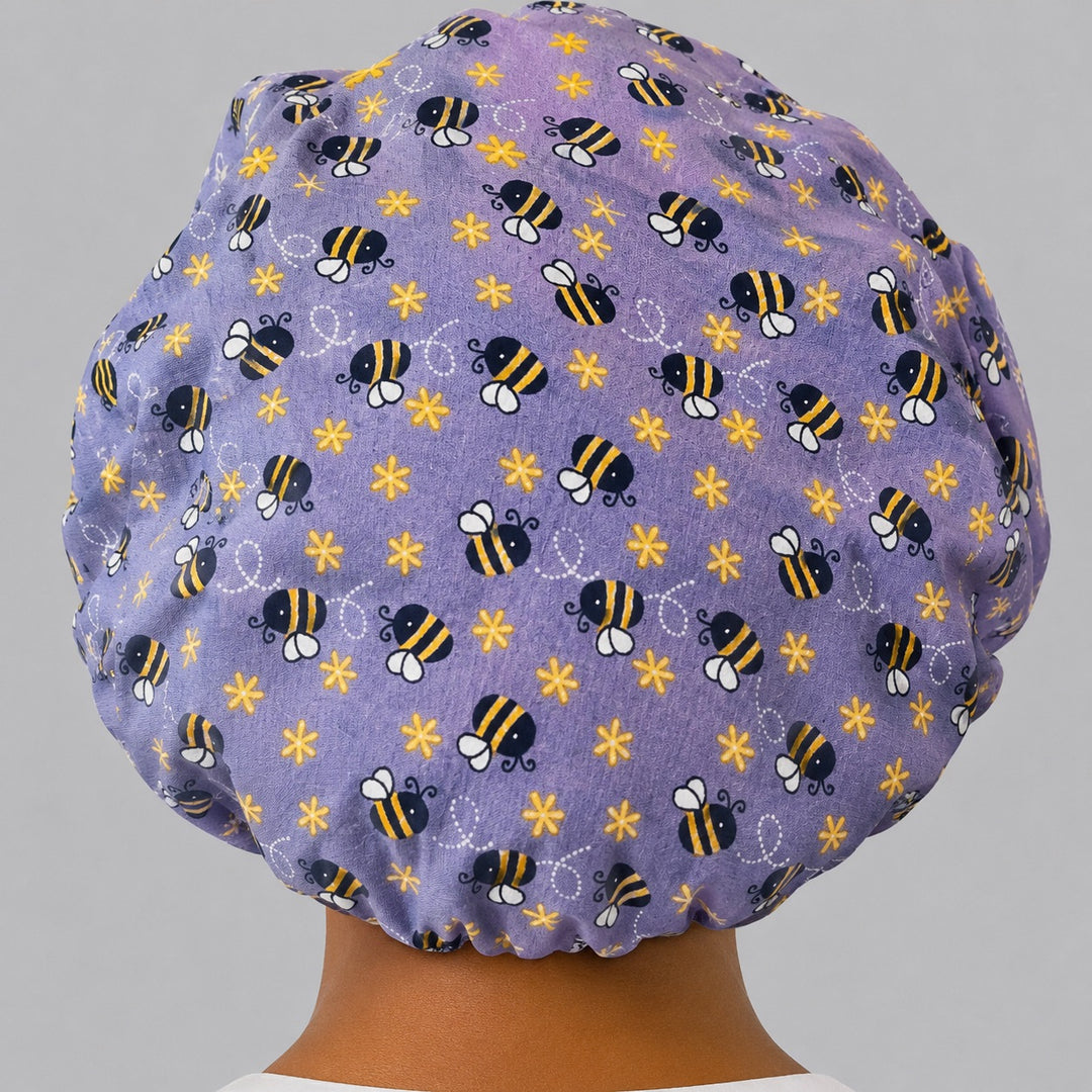 Back view of the purple bee bouffant scrub cap showing the full roomy fit and elastic gathered back — lavender bumblebee and flower print