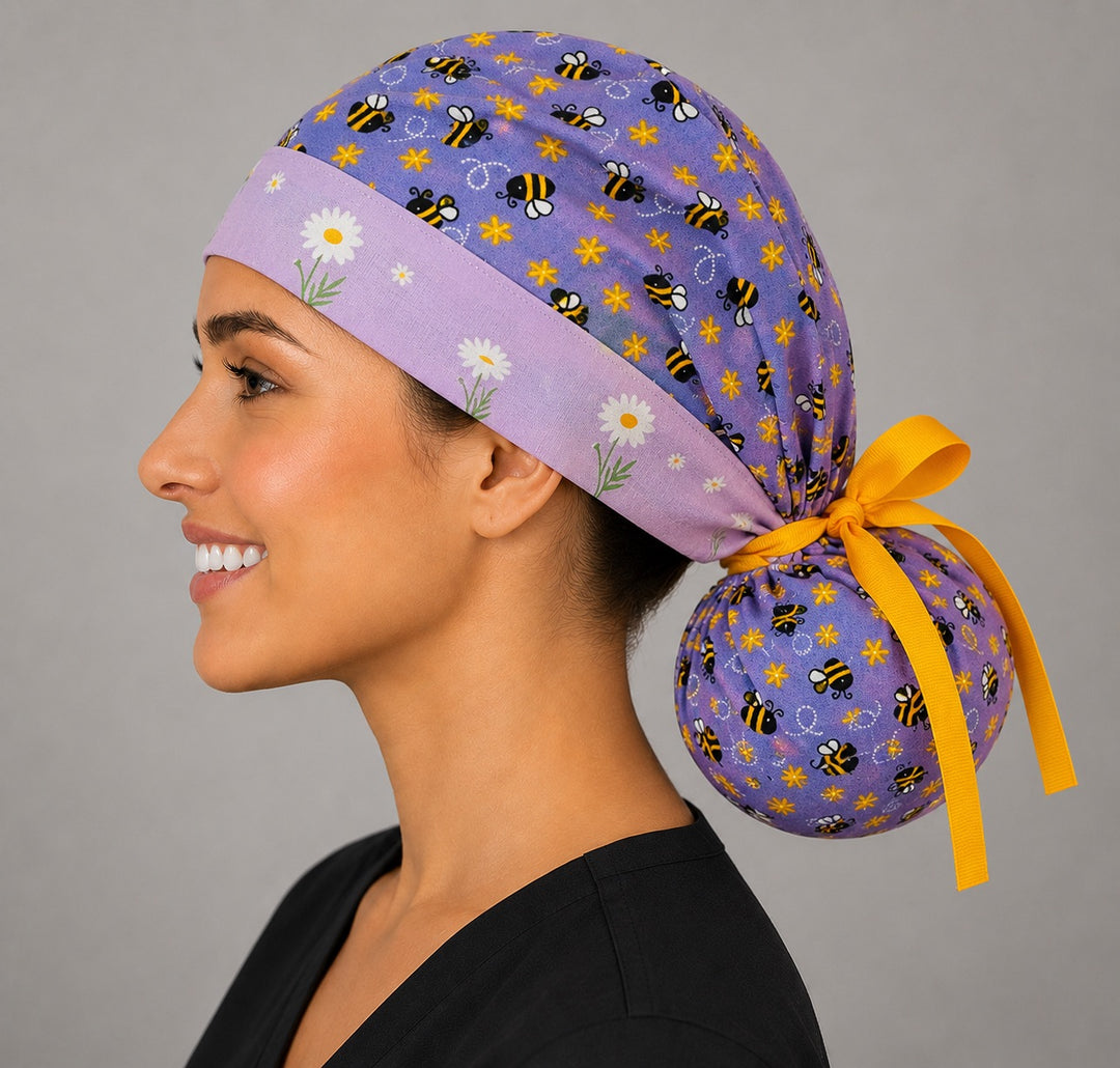 Purple bee and daisy ponytail surgical cap left side profile with daisy band, purple bee print and yellow grosgrain ribbon tie