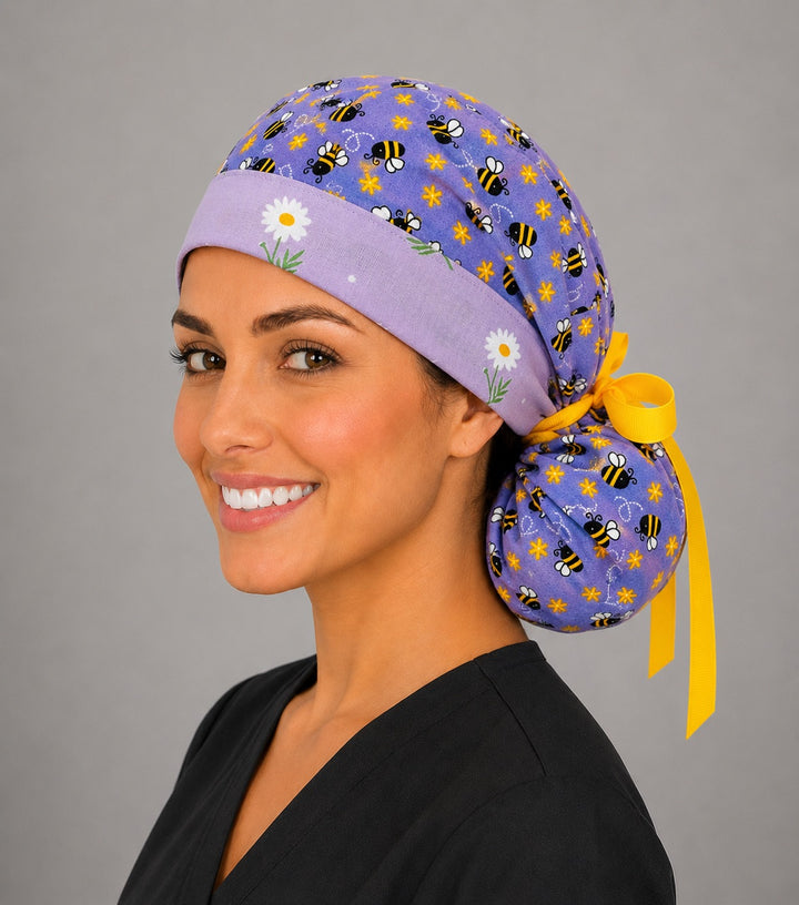Purple bee and daisy ponytail nurse cap right three-quarter angle on smiling model showing bumblebees, purple print, daisy band and yellow ribbon bow