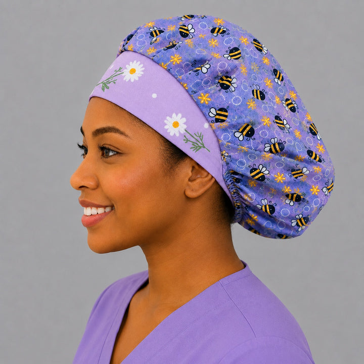 Angled view of the purple bumblebee bouffant scrub cap for women on a smiling nurse — handmade lavender floral surgical cap, USA made