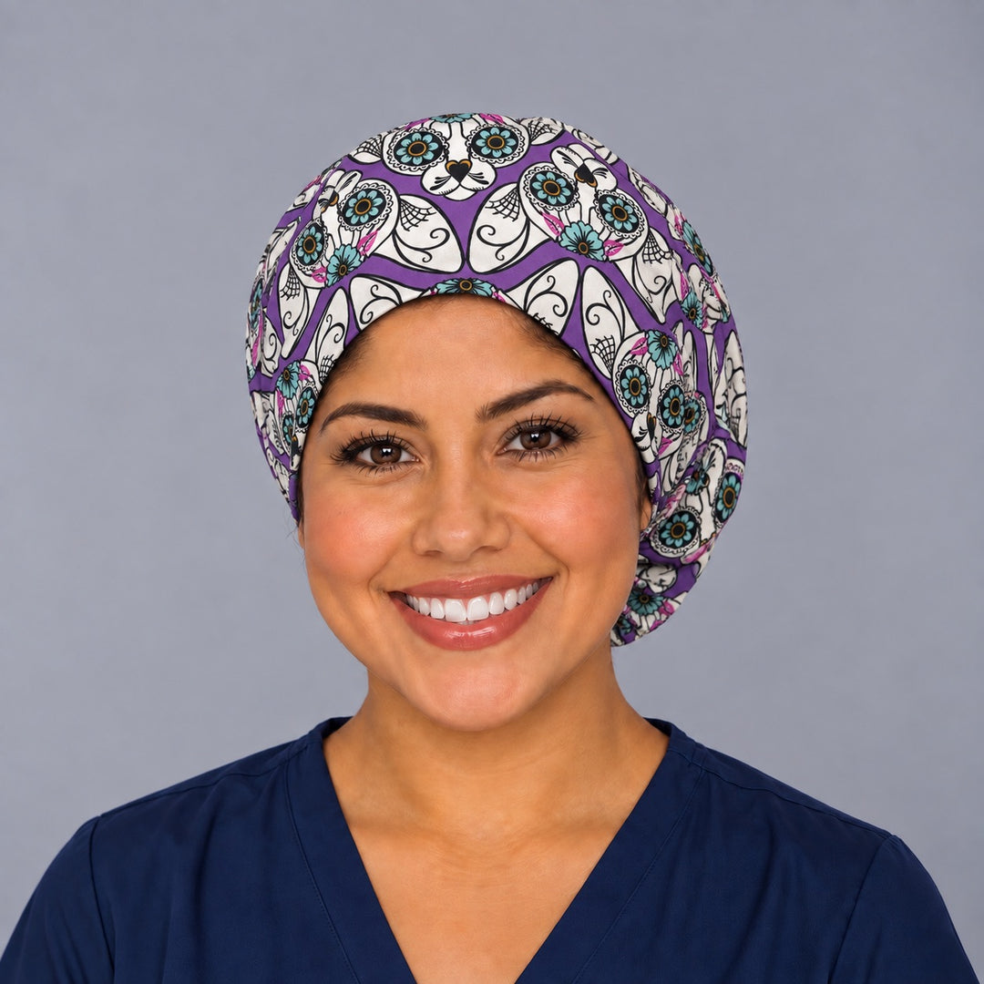 Nurse wearing a purple sugar skull cat Euro scrub cap, front view, Mexican Día de los Muertos surgical hat with teal flower-eyed calavera cats