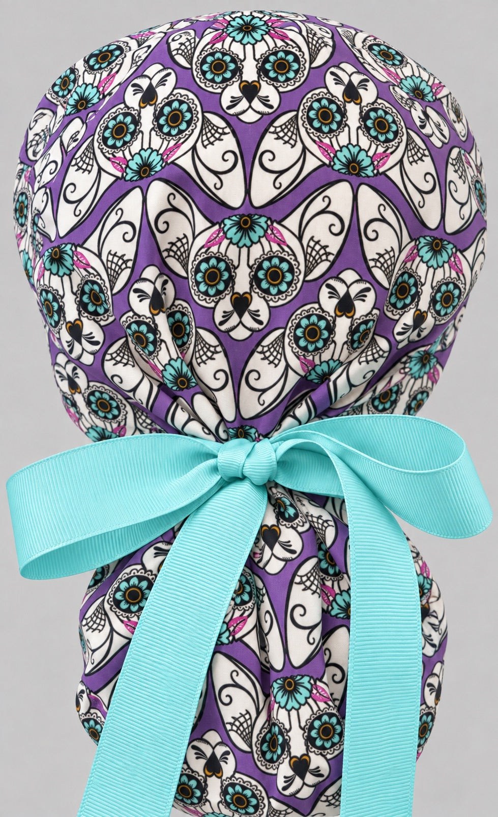 Back view of the purple sugar skull cat ponytail cap — full print close-up with aqua ribbon tie on the pony pouch