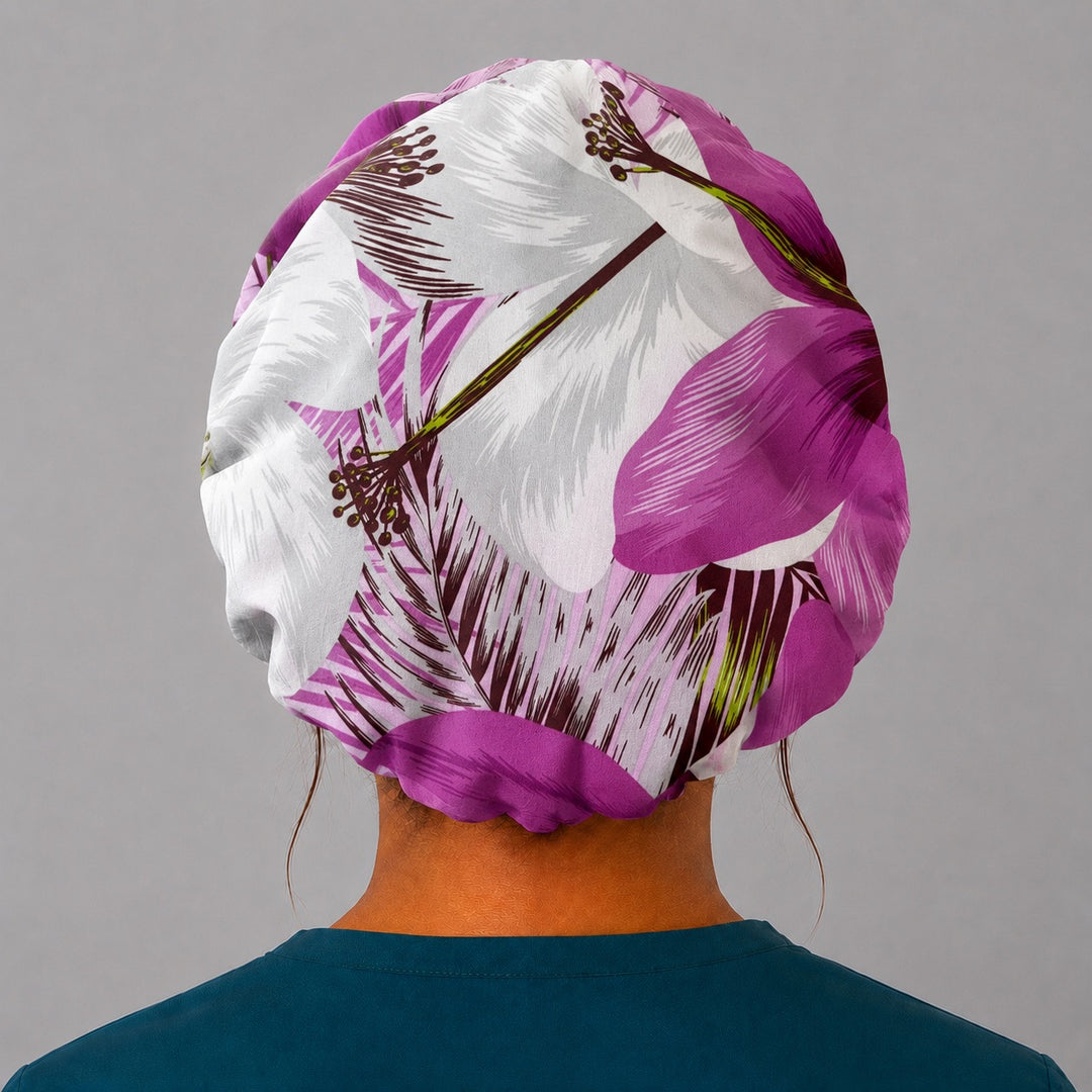 Purple tropical floral bouffant scrub cap back view showing full print of violet and plum hibiscus blooms and palm fronds on cream, OR World surgical hat