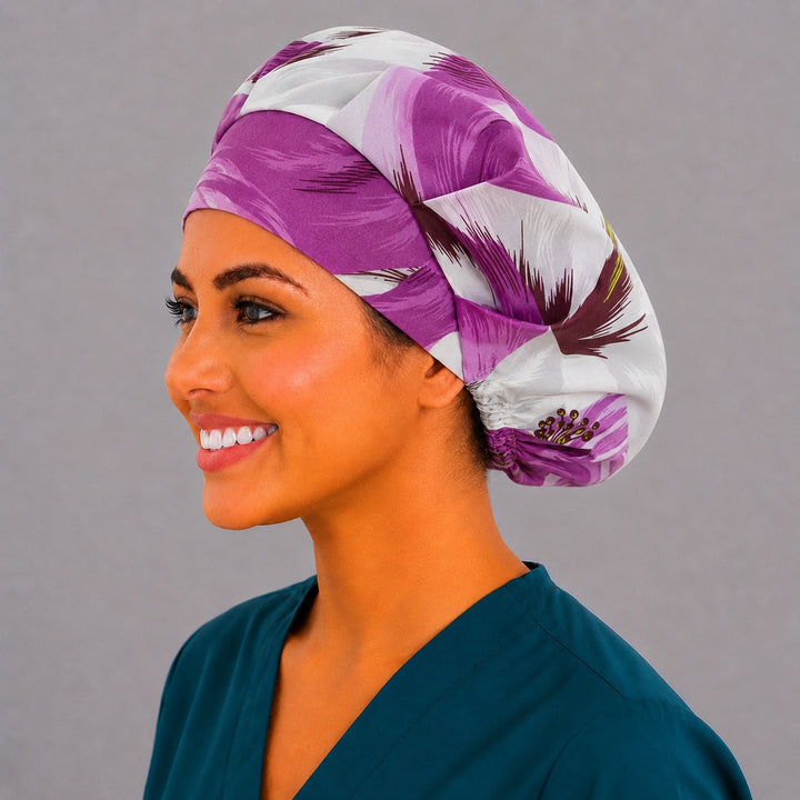 Purple tropical floral bouffant surgical cap left side profile showing violet and plum hibiscus blooms on cream, OR World nurse hat