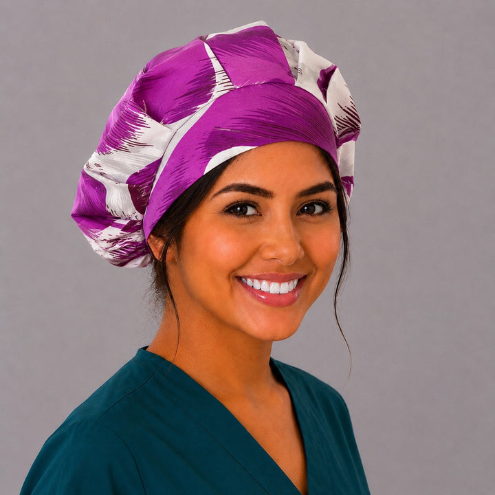 Purple tropical floral bouffant scrub cap right three-quarter angle on smiling model showing violet and plum hibiscus blooms on cream, OR World nurse hat