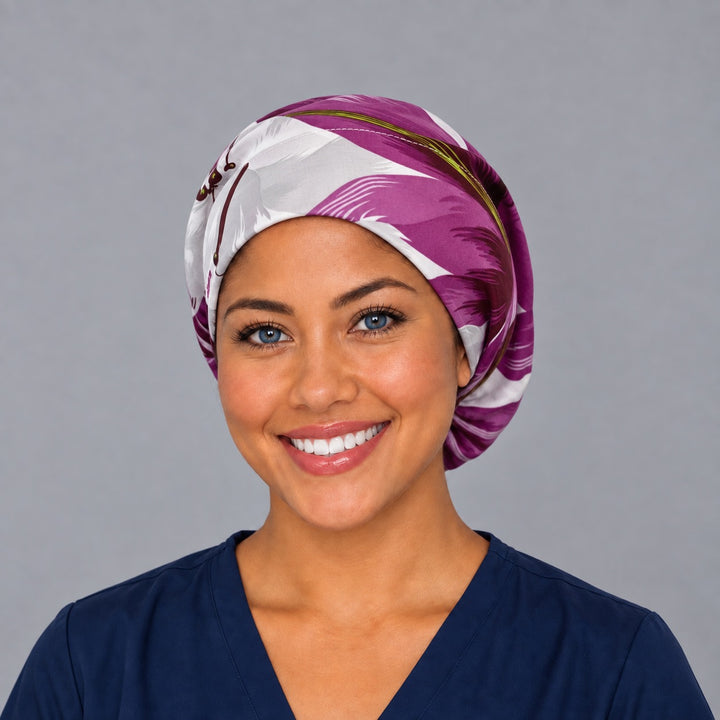 Woman wearing a purple tropical floral Euro scrub cap, front view — magenta and white palm leaves, adjustable women&
