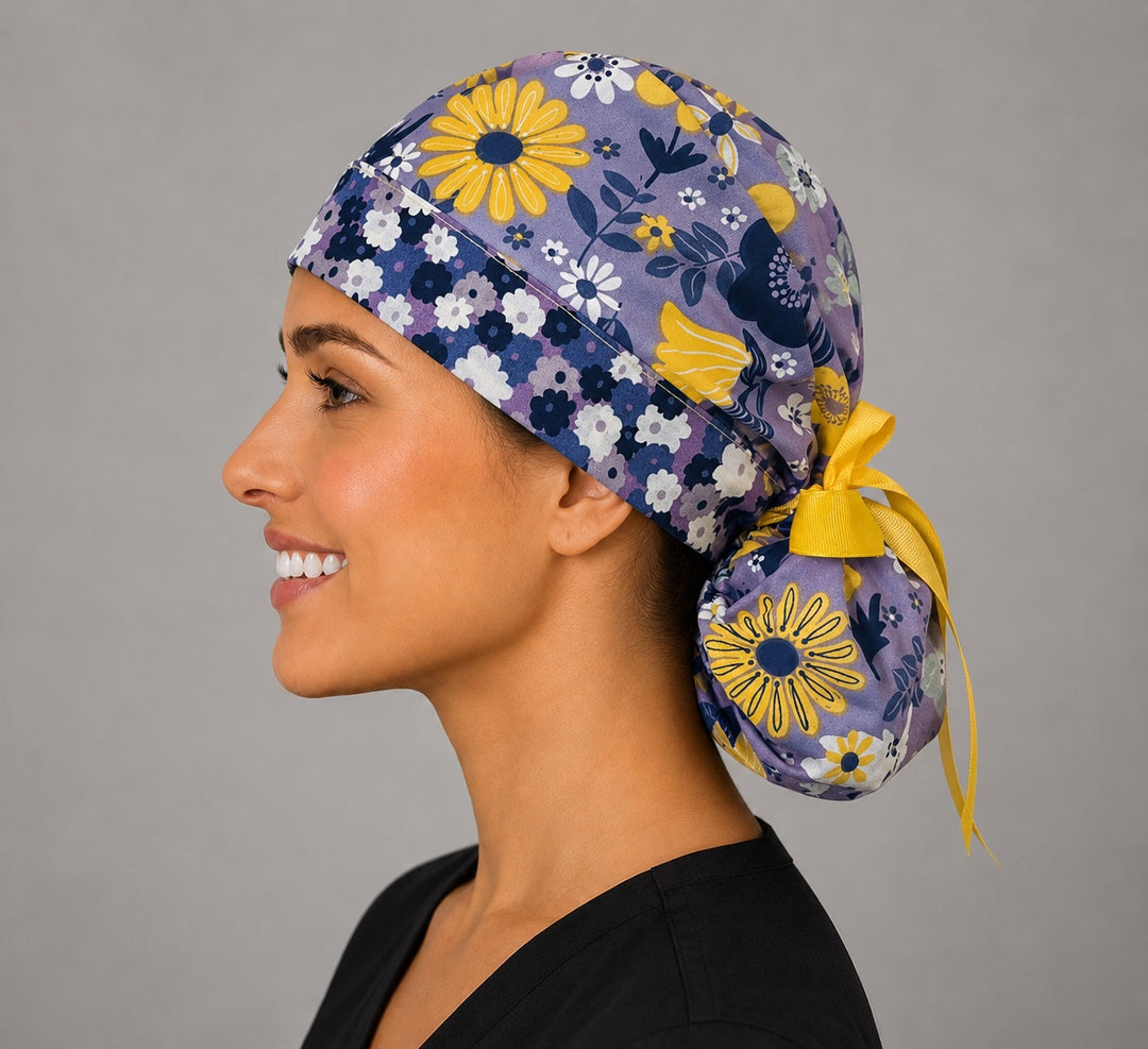 Purple and yellow floral ponytail surgical cap left side profile showing gathered ponytail pouch of summer wildflowers and yellow grosgrain ribbon tie