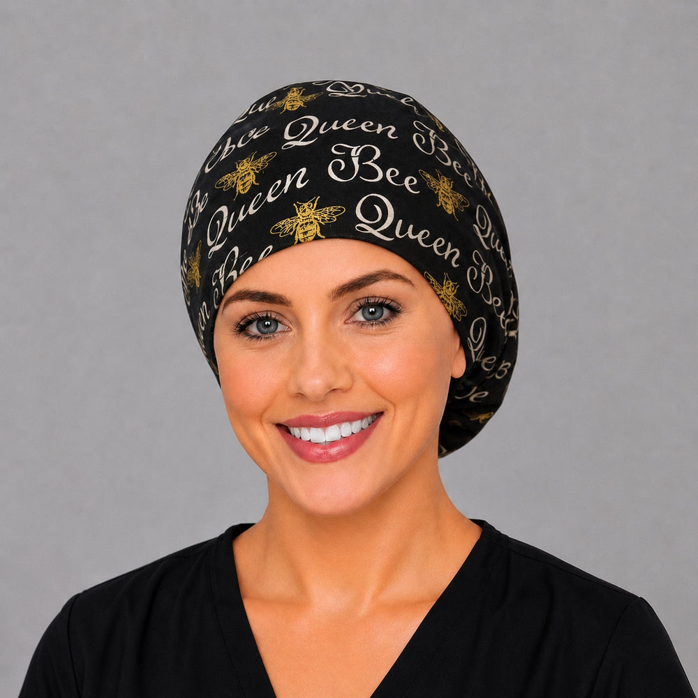 Woman wearing a Queen Bee Euro scrub cap, front view — gold bees and Queen Bee script on black, adjustable surgical hat for nurses
