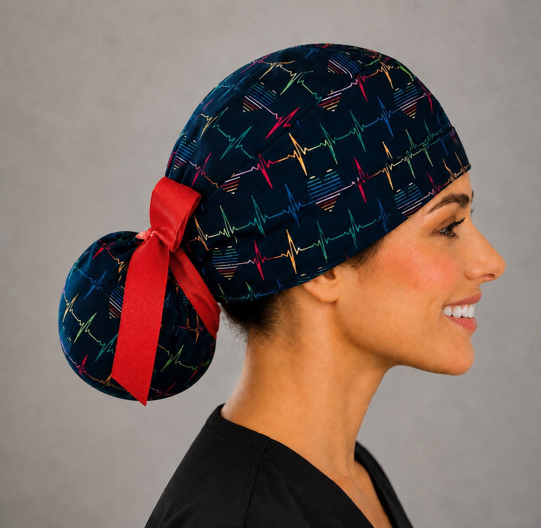 Rainbow EKG heartbeat ponytail scrub cap right side view showing gathered ponytail pouch of colorful heartbeat lines and hearts on navy with red ribbon bow