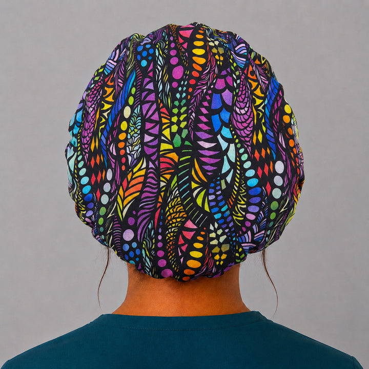Rainbow mosaic bouffant surgical cap right three-quarter angle on smiling model, colorful mosaic on black, OR World Pride nurse hat