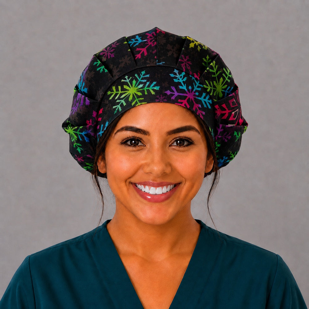 Woman wearing a rainbow snowflake bouffant scrub cap, front view — colorful snowflakes on textured black, adjustable women's surgical hat
