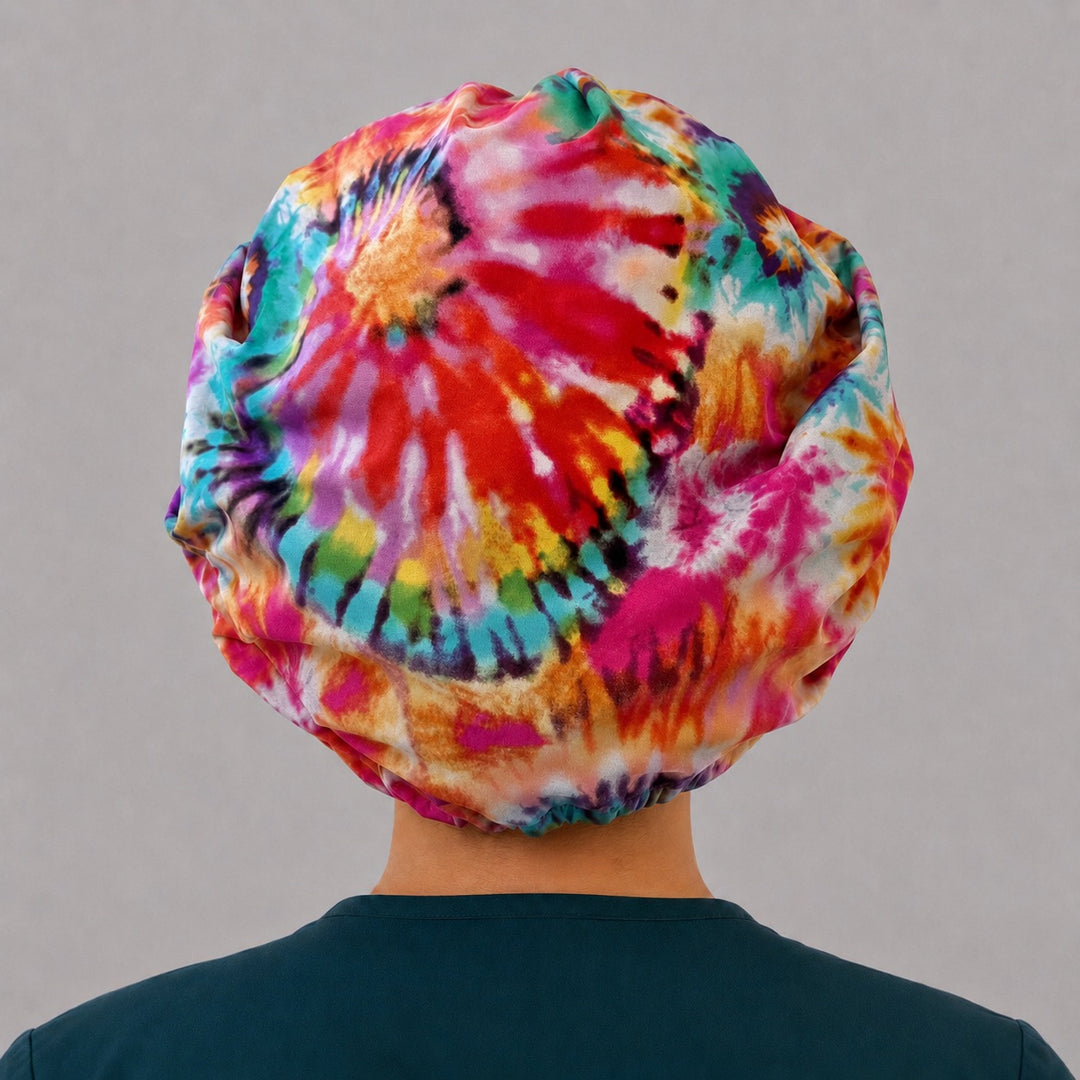 Right side profile of the rainbow tie-dye bouffant surgical hat — fuchsia, orange and teal spiral print, roomy breathable cotton cap for nurses