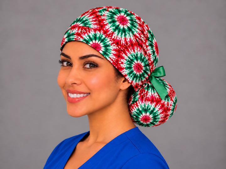 Red green and white tie-dye ponytail scrub cap, left three-quarter view, Mexican fiesta and Christmas surgical hat for long hair with green bow