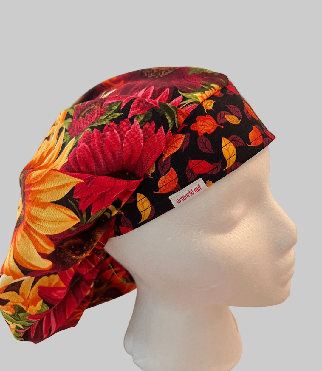 Red sunflower fall bouffant scrub cap with gold, orange & burgundy sunflowers and a fall-leaf band, front view — handmade-in-USA surgical hat for women from OR World.