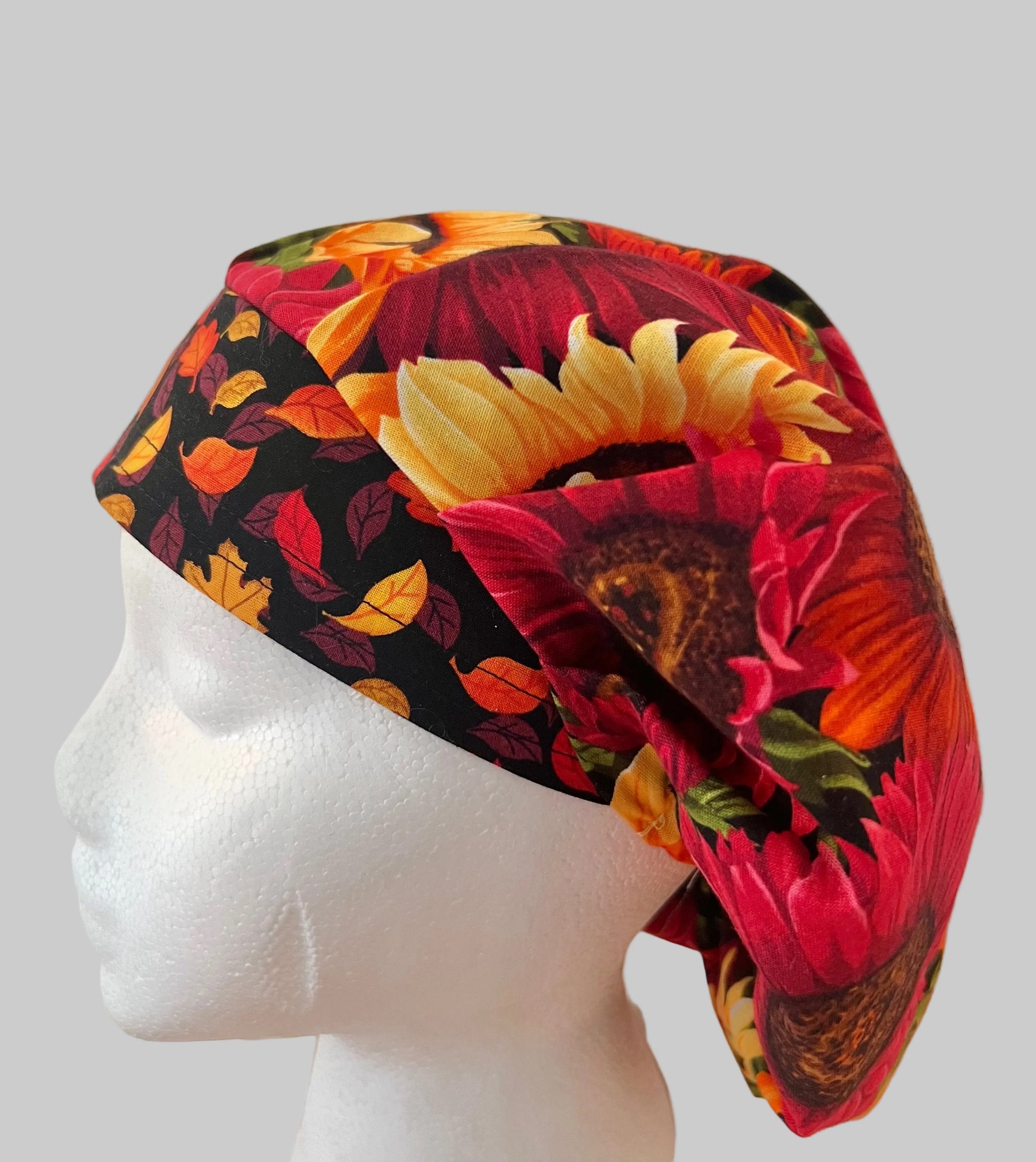 Side profile of red sunflower fall bouffant scrub cap with orworld.net label — handmade-in-USA autumn surgical hat for women with long hair.